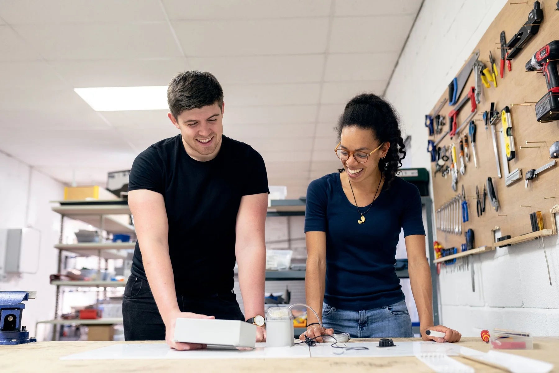 Two engineers collaborating over a physical prototype in a workshop