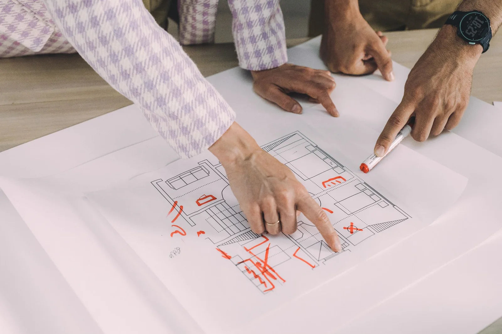 Hands of a small design group discussing an architectural floor plan